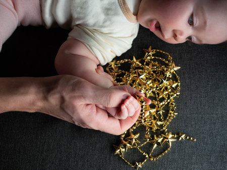 Closeup of father holding baby hand on sofa background. Baby wonder christmas ornamentの写真素材