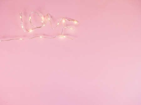 Flat lay electric lights put in love text on pink background with copy space. Concept of Valentines, anniversary, mothers day greetingの写真素材
