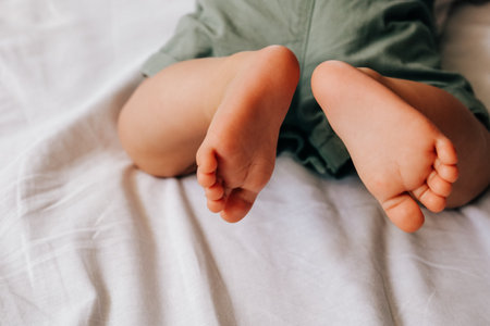 Closeup view of 8 month baby boy feet on white sheetの写真素材