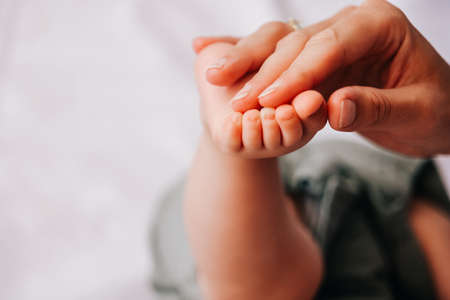 Closeup of mother holding baby hand on white sheet. Happy motherhoodの写真素材