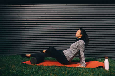 Young fit woman exercising butt using foam roller at gym. High quality photoの写真素材