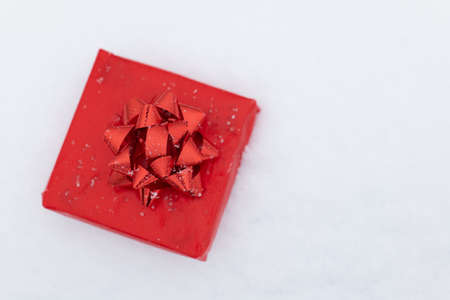 Closeup view of red gift box lying in snow copy space. Christmas and valentines day holidaysの写真素材