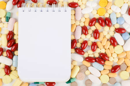 White open notepad on variety of different pills and capsules background. Healthcare and Medicineの写真素材