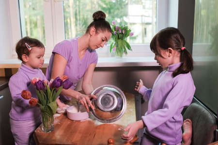 Happy loving family preparing bakery together in the kitchen. Mother and two child daughters cooking apple pie. Homemade food and little helpers. Preparing doughの写真素材