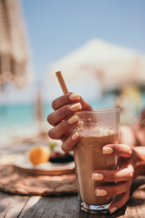 Ice coffee latte on the beach. Summer iced coffee latte in tall glass with straw by the sea in beach bar coffee latte on the beach.の写真素材