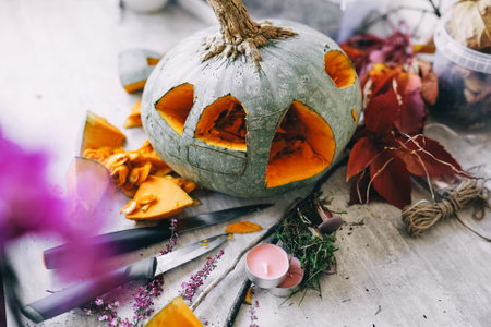 Preparing Halloween decorations, cutting windows on pumpkin. Making beautiful autumn lantern from pumpkin.の写真素材