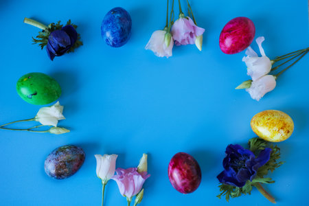 Beautiful spring flowers and easter eggs put in frame on blue background. Top view with copy space. Happy easter greeting card.の写真素材