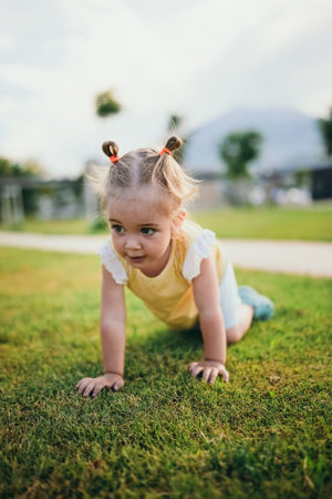 Adorable 2 years old playing on the grass outdoors at park, summer timeの写真素材