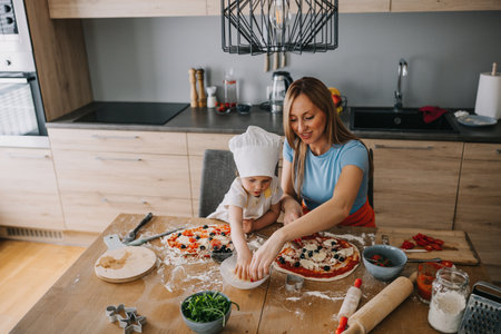 Funny family daughter and mother making pizza for dinner at the kitchen. Happy family together.の写真素材