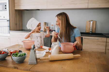 Funny family daughter and mother making pizza for dinner at the kitchen. Happy family together.の写真素材