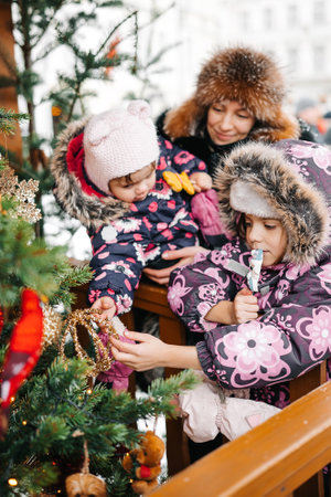 Happy family spend time at a Christmas street market fair in the old town Tallinn in Estonia. Mother...