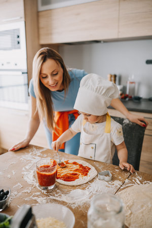 Funny family daughter and mother making pizza for dinner at the kitchen. Happy family together.の写真素材