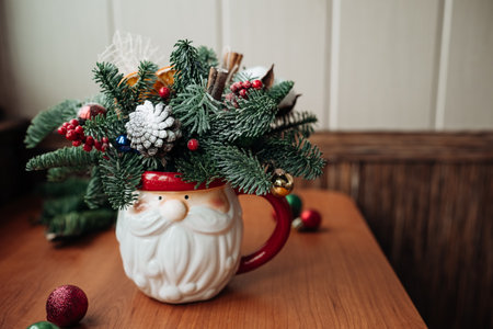 Winter Christmas bouquet, fir tree branches compositions with Christmas decorations in funny bowl on the table by the window. Christmas decor. Home winter holiday concept.の写真素材