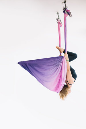Fly yoga women practicing fly yoga hanging upside down in hammock on white background. Fit woman...