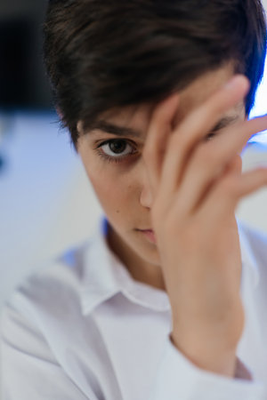 portrait of cute teenager hiding half of his face behind hand. Looking at cameraの写真素材