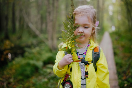 Happy preschooler girl walking in early autumn forest in the bog with backpack. Activities with children outdoorsの写真素材