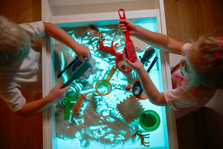 Preschoolers playing with sand on sensory box in the kids roomの写真素材