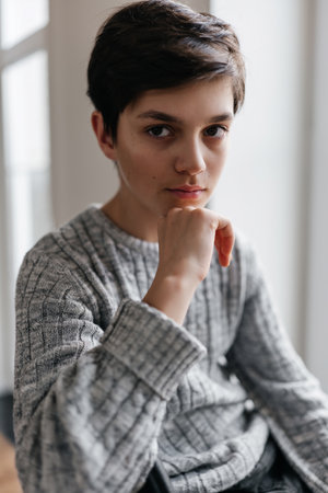 portrait of a pretty teenager sitting on the chair indoors. Looking at cameraの写真素材