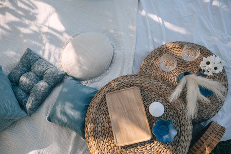 Woven tables with a wooden tray sit among various cushions and floral decorations in a relaxing...