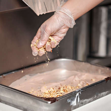 Making Of Ice Cream - Pouring nuts in the steel pan with ice cream in the small manufacturing - close upの写真素材