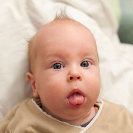Adorable 3 month old baby boy sticking tongue out - first wordsの写真素材
