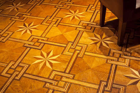 Vintage ornament. Decorative pattern parquet floor with part of emty chair in corner