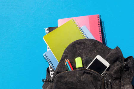 Spiral notebooks coming out of a black schoolbag, penciles and mobile phoneの写真素材