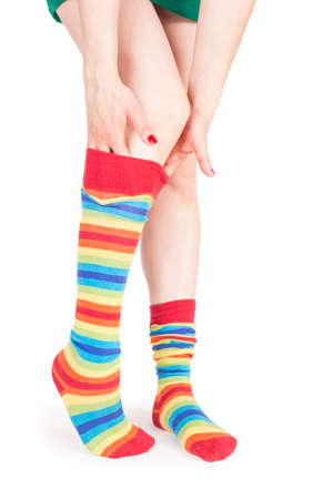 Perfect long female legs in rainbow pantyhose - isolated on white background - adjusting a stockingの写真素材