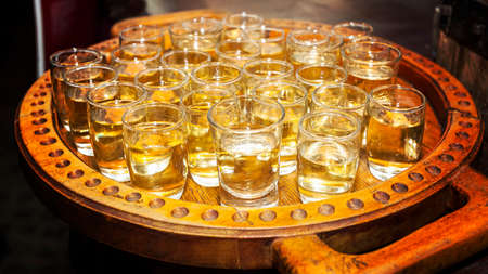 Traditional serbian brandy called rakija - small glasses filled with fruit brandy on a wooden trayの写真素材