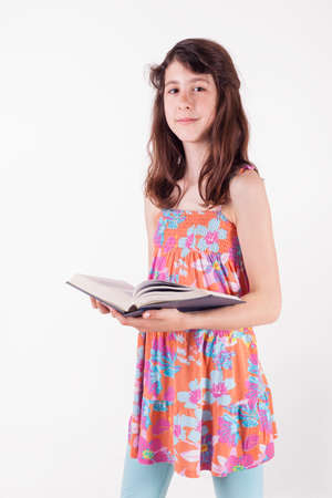 Teenage girl standing with a book, studying, studio isolated on whiteの写真素材