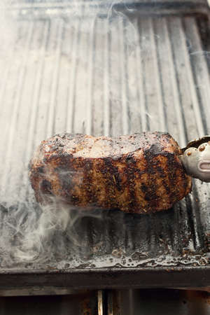 smoking, sizzling beef steak on a grill