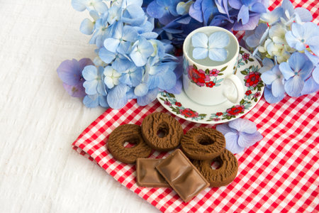 cup of tea on the table with hydrangea flowers and biscuits aroundの写真素材