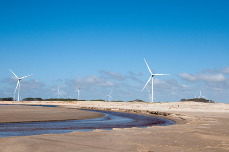 Wind turbines on beach with blue sky and clouds