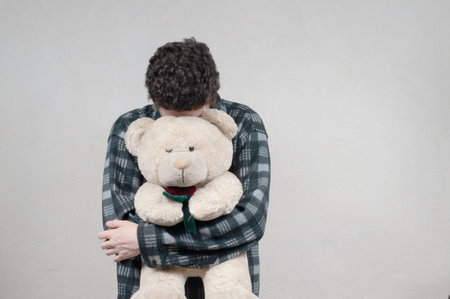 Young man holding a cute teddy bearの写真素材