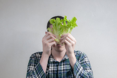 Young man holding lettuce with gray backgroundの写真素材