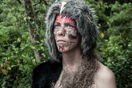 Portrait of a beautiful boy with a painted face in the forest