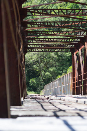 Old rusty iron bridge over the river in the forestの写真素材