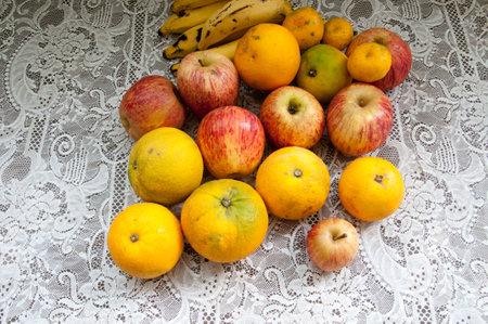 Ripe apples and bananas on a white lace tablecloth, top view