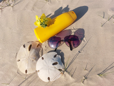Pot of bronzer in the dunes with shells and sunglasses aroundの写真素材