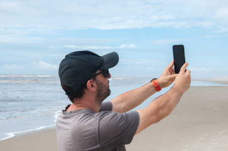 View of a Young attractive man taking a selfie on the beach.の写真素材