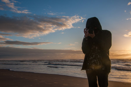 silhouette of a man with a camera on the beach at sunset