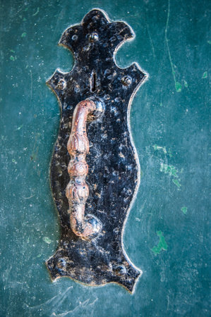 Old door handle on grunge green wooden background, vintage style.