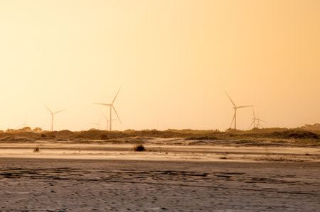 Wind turbines on the beach in the evening at low tide. Ecological conceptの写真素材