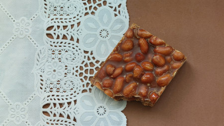 Chocolate candy with peanuts on a white lace napkin on a brown backgroundの写真素材