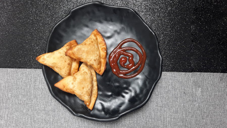 Fried pastries on top of a black plate with ketchupの写真素材