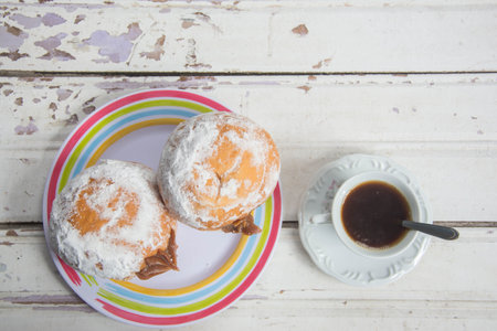 Cup of coffee and Berliner on white wooden table. Top viewの写真素材
