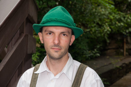 Handsome young man in traditional Bavarian clothes with a green hatの写真素材