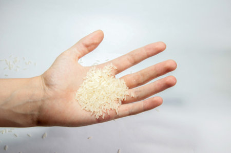 White rice in hand on a white background. Selective focus.の写真素材