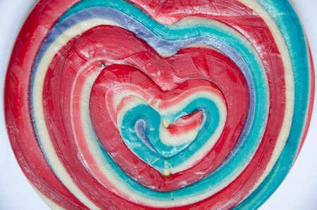 Colorful lollipop in the shape of a heart on a white backgroundの写真素材