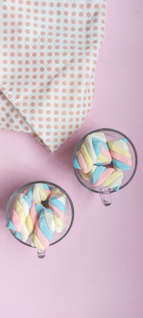 Colorful marshmallows in a glass vase on a pink backgroundの写真素材